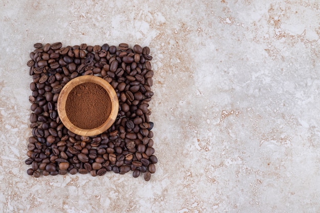 Foto gratuita recipiente pequeño con café en polvo rodeado de una pequeña pila de granos de café.