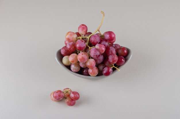 Recipiente pequeño con racimo de uva sobre mármol