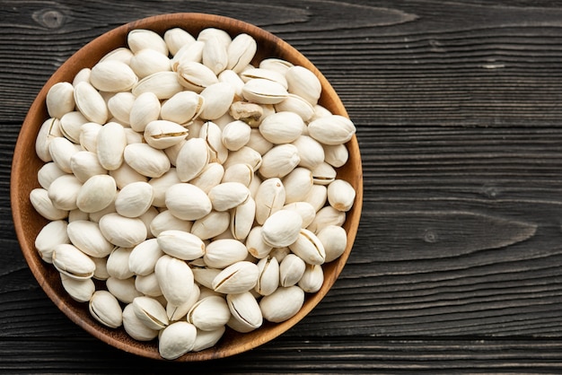 Foto gratuita recipiente con pistachos sobre una mesa de madera.