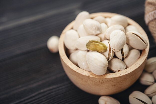 Recipiente con pistachos sobre una mesa de madera.