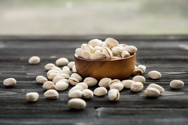 Recipiente con pistachos sobre una mesa de madera.