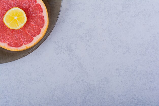 Recipiente de vidrio de rodaja de pomelo fresco con limón sobre piedra.