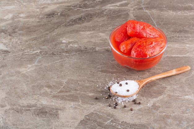 Foto gratuita recipiente de vidrio de tomate en escabeche y sal sobre la mesa de piedra.