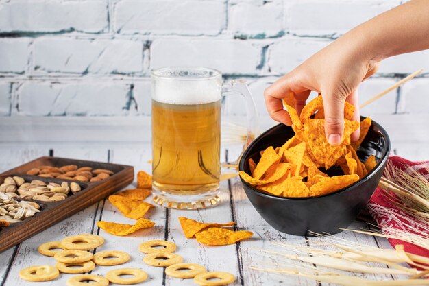 Recogiendo papas fritas del tazón en una mesa de cerveza