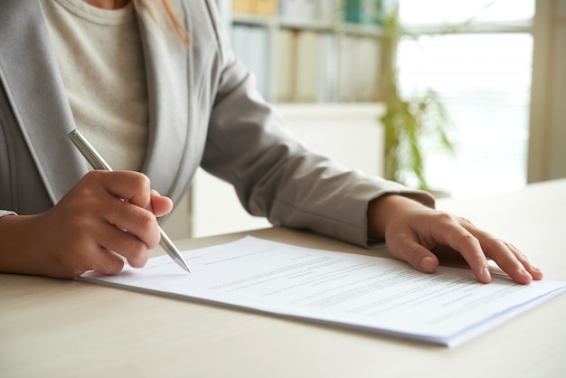 Recorta la sección media de una mujer irreconocible que firma el documento