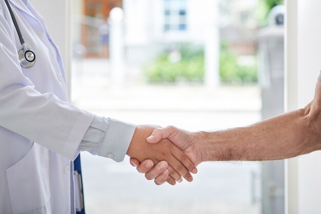 Recortado médico irreconocible y paciente estrechándole la mano