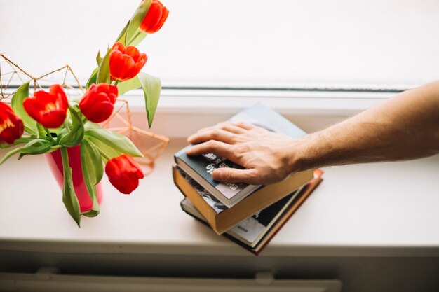 Recortar la mano en los libros cerca de las flores