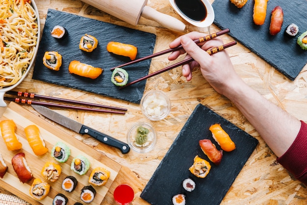 Recortar mano tomando sushi del tablero