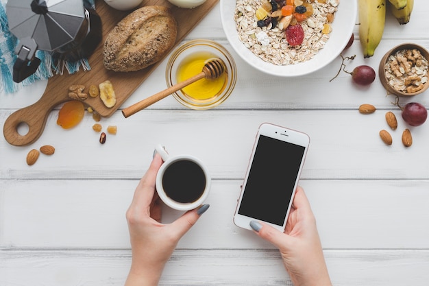 Recortar las manos con café y teléfono inteligente