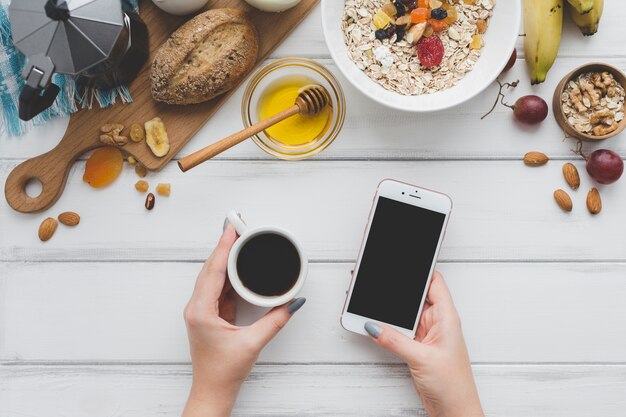 Recortar las manos con café y teléfono inteligente