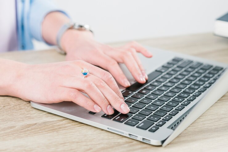 Foto gratuito recortar las manos escribiendo en la computadora portátil en la oficina