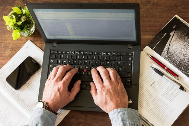 Recortar las manos escribiendo en la computadora portátil en la oficina