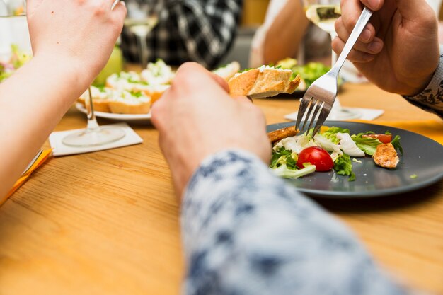 Recortar las manos del hombre comiendo delicioso plato