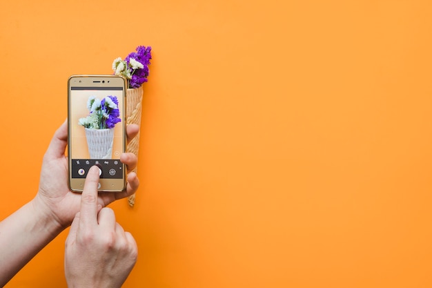 Foto gratuita recortar las manos mostrando flores en el teléfono inteligente
