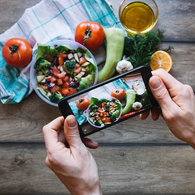 Recortar manos tomando fotos de ensalada