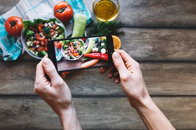 Recortar manos tomando fotos de ensalada