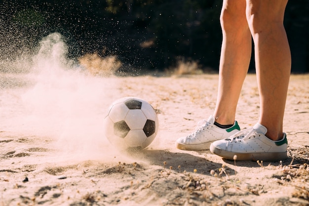 Foto gratuita recortar las piernas atléticas de pie por fútbol al aire libre