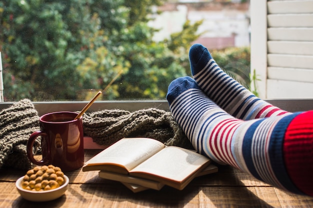 Recortar las piernas cerca de libros y bebidas calientes.