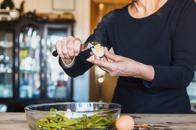 Recorte las manos de la mujer mayor que cocina el plato delicioso en cocina