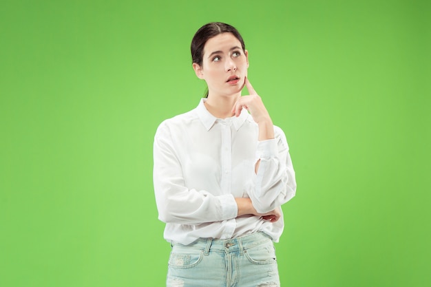 Recuerda todo. Déjame pensar. Concepto de duda. Mujer dudosa y pensativa recordando algo. Joven mujer emocional. Las emociones humanas, el concepto de expresión facial. Estudio. Aislado en verde de moda