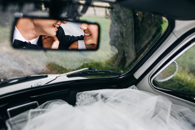 Reflejo de caras sonrientes de recién casados en la ventana rara de un ca