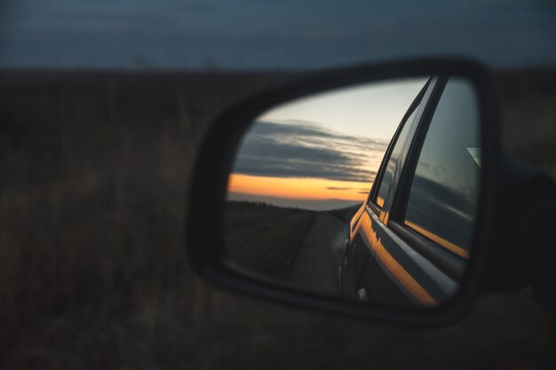 Reflejo de la hermosa puesta de sol a través del retrovisor del automóvil