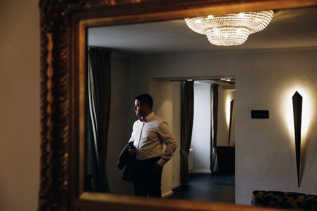 Foto gratuita reflejo de un hombre en esmoquin de pie ante la ventana en un mi