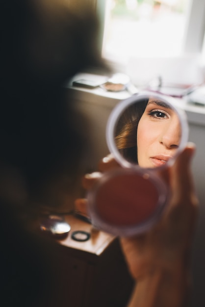 Reflejo del rostro de una mujer hermosa en el espejo en sus brazos.