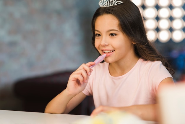 Reflejo de la sonriente joven aplicando lápiz labial en los labios