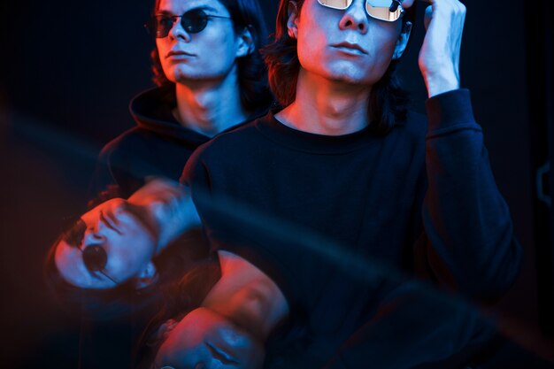 Reflexión clara. Retrato de hermanos gemelos. Foto de estudio en estudio oscuro con luz de neón