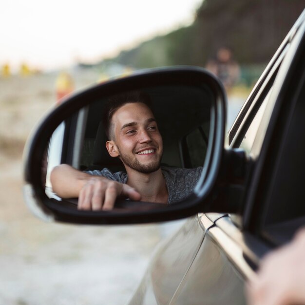 Reflexión del hombre en el espejo del coche