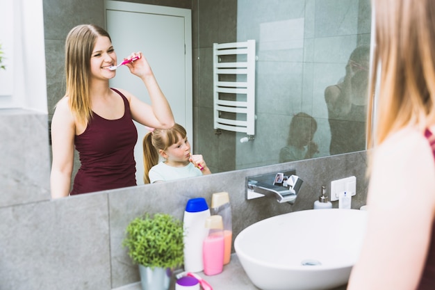 Foto gratuita reflexión de madre e hija cepillarse los dientes