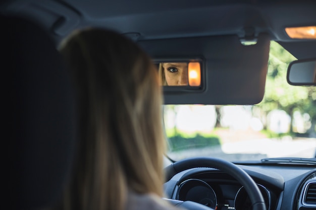 Reflexión de una mujer en el espejo retrovisor del coche