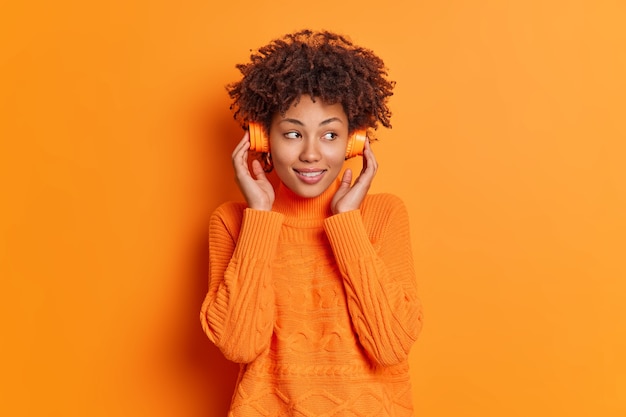 Reflexiva mujer milenaria bonita con cabello afro escucha música concentrada a un lado