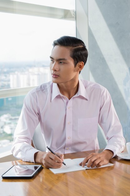 Reflexivo Hombre asiático joven que trabaja en café