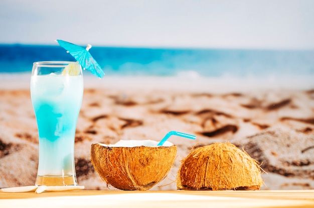 Refrescante cóctel azul y leche de coco en playa de arena