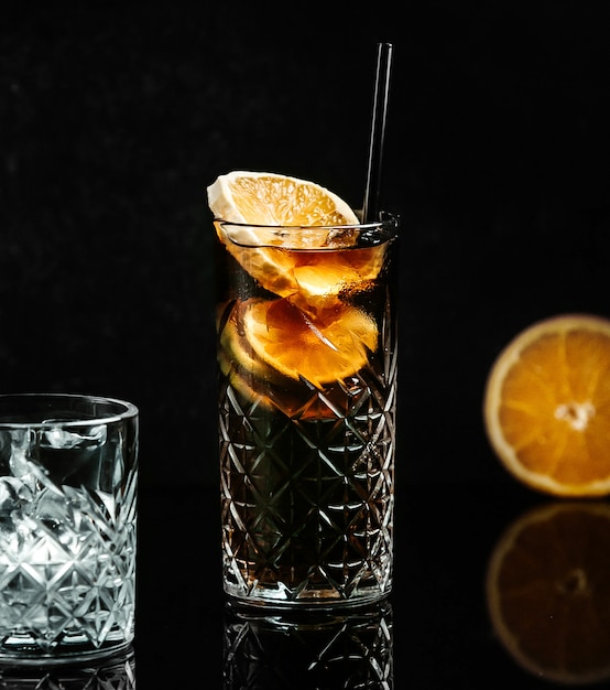 Refresco en vaso negro con rodaja de limón