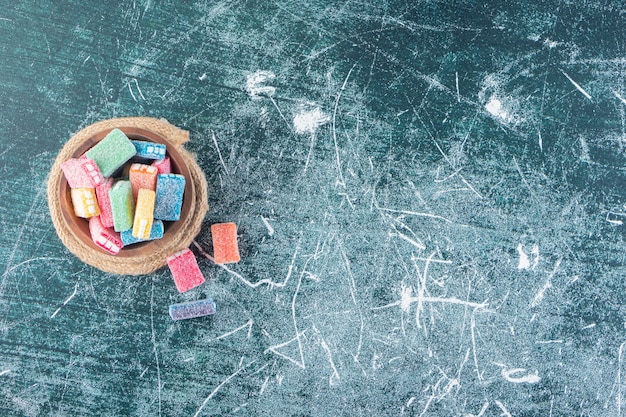 Foto gratuita regaliz de colores en un recipiente hondo colocado sobre la mesa de piedra.