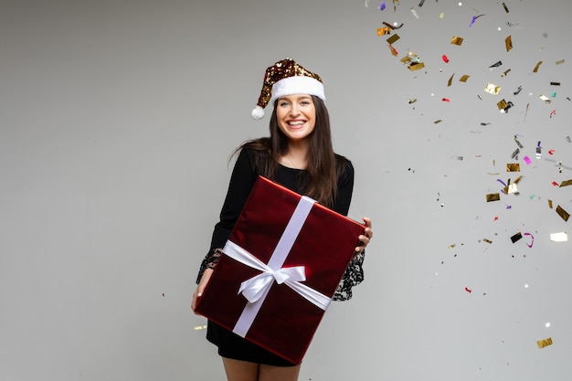 Regalo de año nuevo de Navidad en manos femeninas, niña feliz con sombrero de santa celebrando las vacaciones de invierno