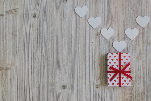 Foto gratuita regalo con un lazo rojo con corazones blancos