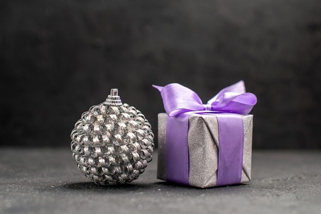 Regalo de navidad de vista frontal y juguete de bola de árbol de navidad sobre fondo oscuro espacio libre foto de navidad