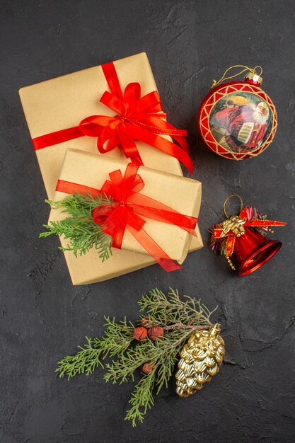 Regalo de Navidad de vista superior en papel marrón atado con adornos de árbol de Navidad de cinta roja sobre fondo oscuro