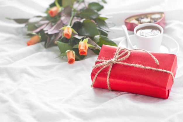 Regalo rojo con bombones, una taza de café y flores