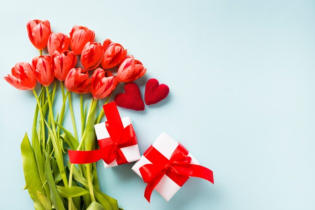 Regalos y corazones cerca de tulipanes