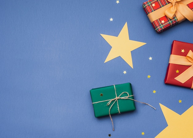 Regalos para navidad sobre fondo azul con estrellas doradas