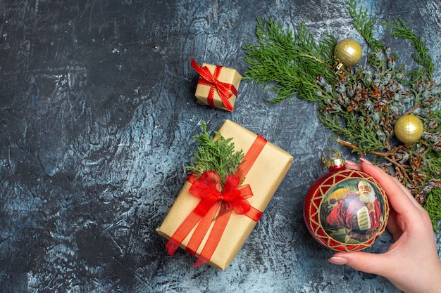 Regalos de Navidad de vista superior con rama verde sobre fondo claro-oscuro