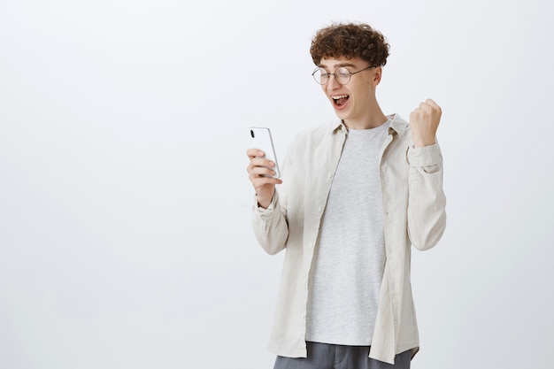 Foto gratuita regocijo chico adolescente posando contra la pared blanca