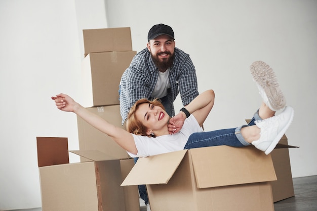 Relajación al sentarse en la caja vacía. Pareja feliz juntos en su nueva casa. Concepción de mudanza