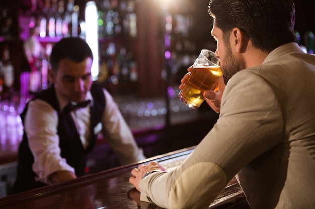 Relajado joven bebiendo un vaso de cerveza