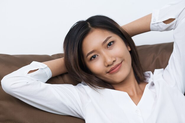 Relajado joven mujer asiática que miente en el amortiguador